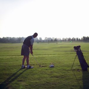 A golfer at a driving range hitting a golf ball